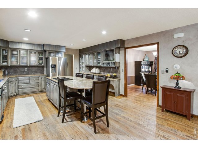 Property Photo 29 Wrap around grand granite island with 5-burner built-in cooktop, Custom Cabinets full tile backsplash, Frosted glass doors for cabinetry Stainless steel appliances, Trash Compactor Stainless Steel hardware for cabinets and drawers. 