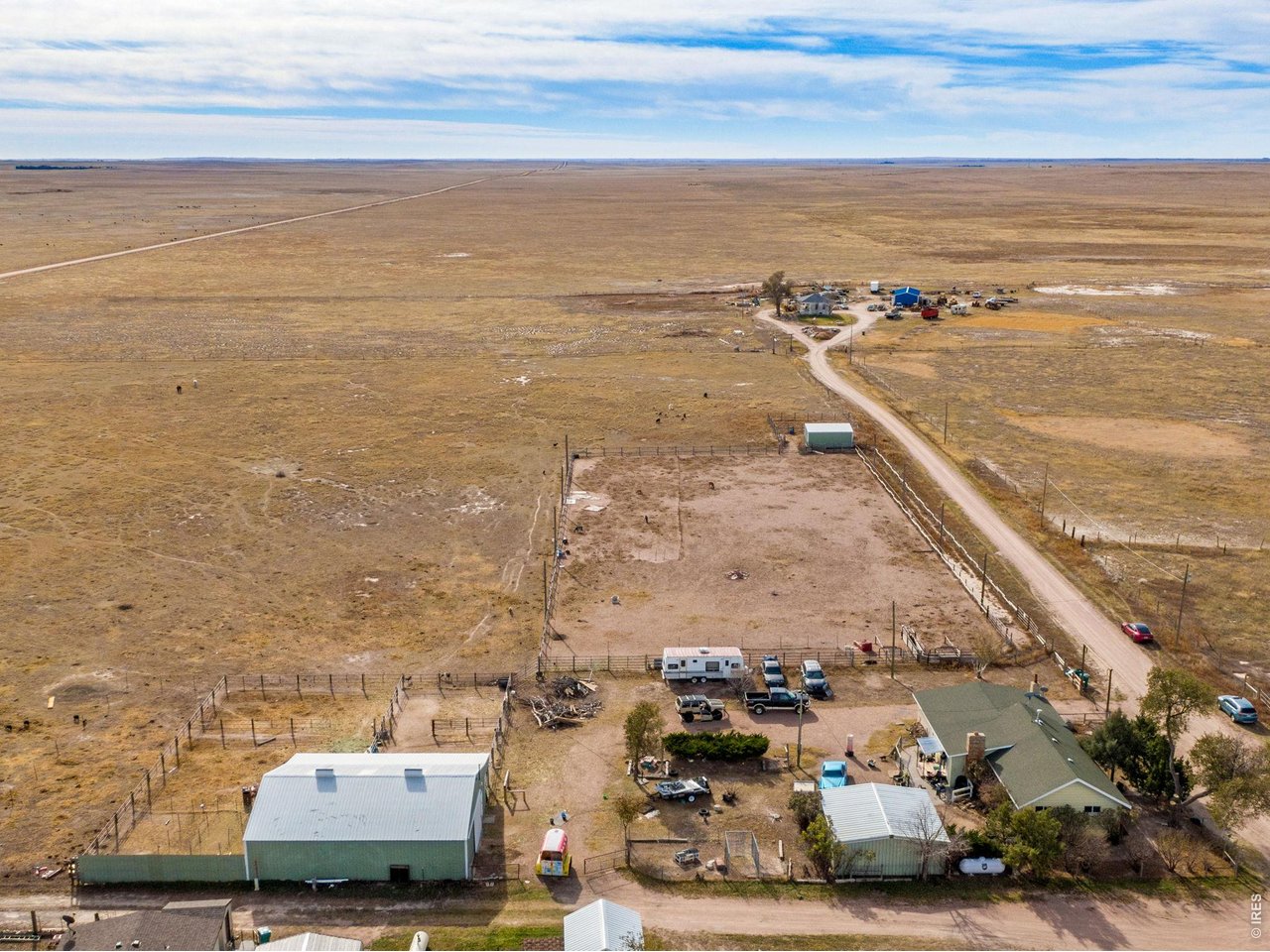 Looking South showing the home, 2 car detached garage, barn and arena.