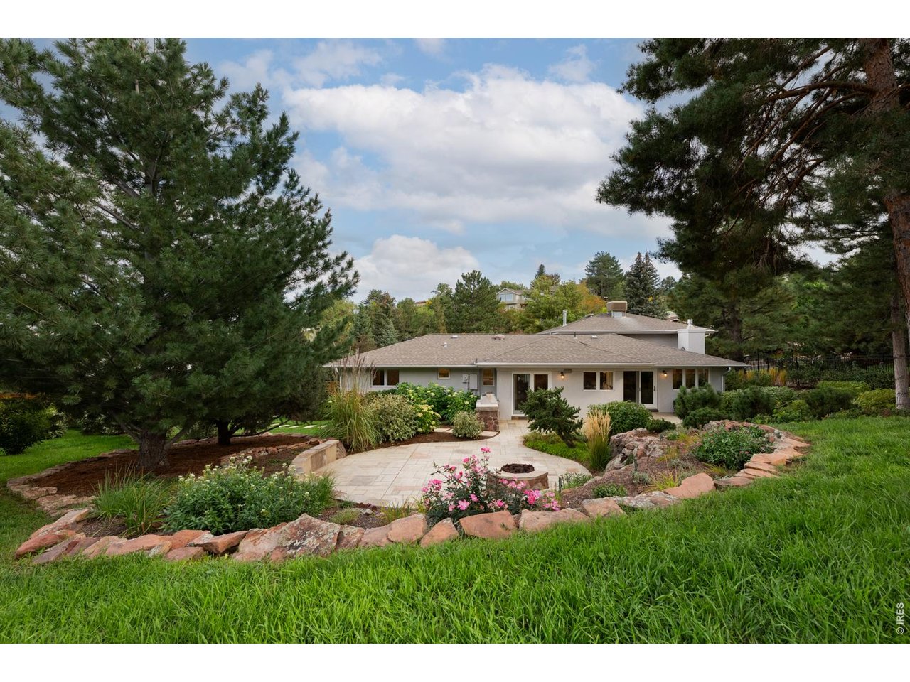 The backyard is an oasis with plenty of space to entertain! Outside, the stunning .59-acre property features an oversized flagstone patio surrounded by rock walls, towering trees, a grill, a fire pit and a charming garden shed.