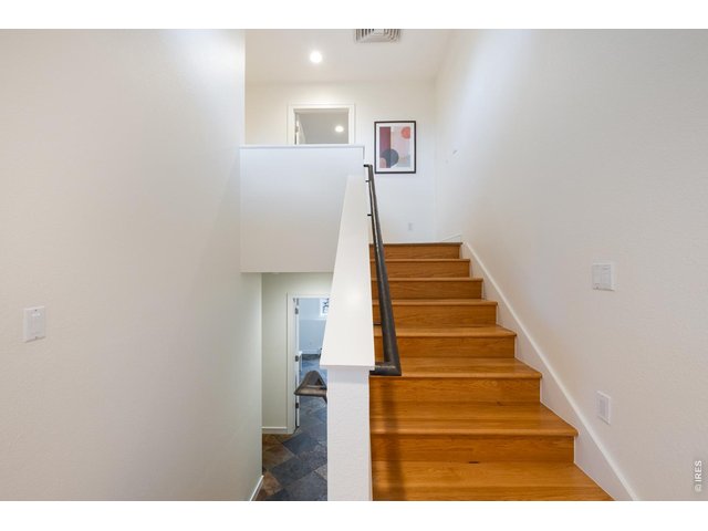 Property Photo 24 Wood staircase leads to private upper level primary suite and additional bedroom.