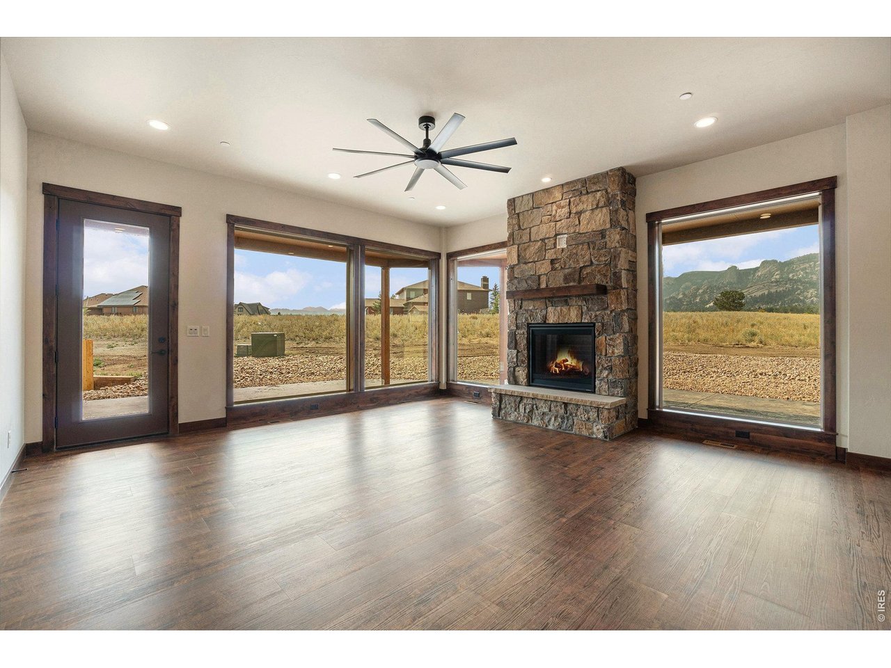 Oversized picture windows frame the stone gas fireplace