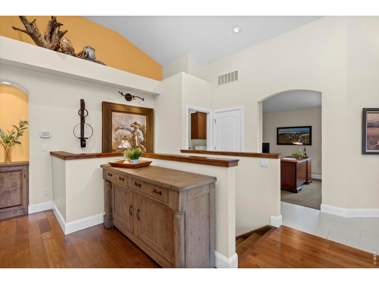 Living view into the front office, open stairway to lower level and hallway to Primary Bedroom