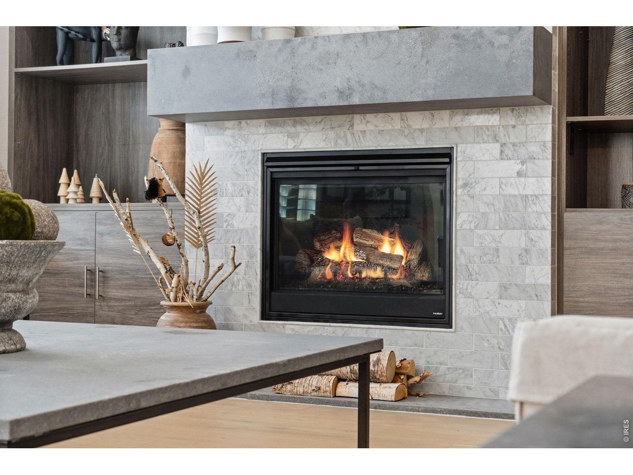 Vaulted ceilings frame a marble-surround gas fireplace - a sculptural focal point that brings texture, warmth, and artistry to the living space. 