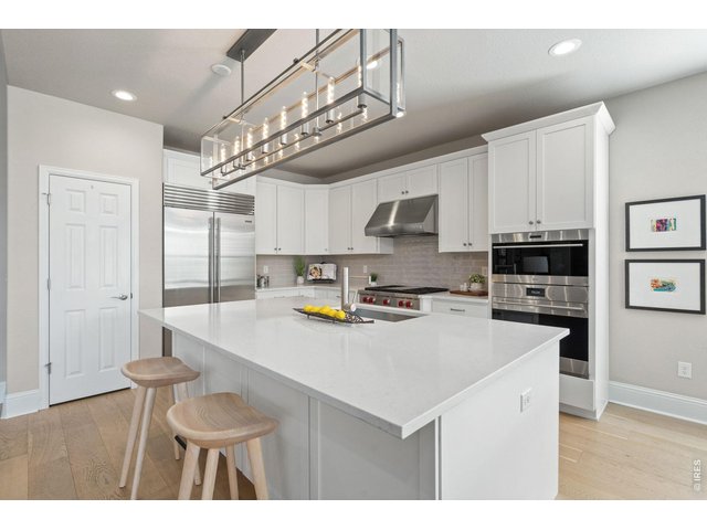 Property Photo 14 A gathering place. A statement of how beautifully life can be lived. A grand quartz island invites gathering and conversation beneath upgraded designer lighting