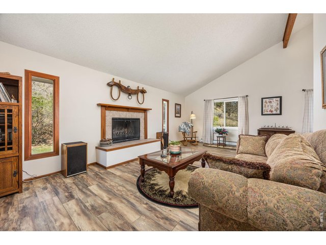 Property Photo 10 Inside, enjoy an open, light-filled layout with vaulted ceilings, large windows, and a cozy wood-burning fireplace.
