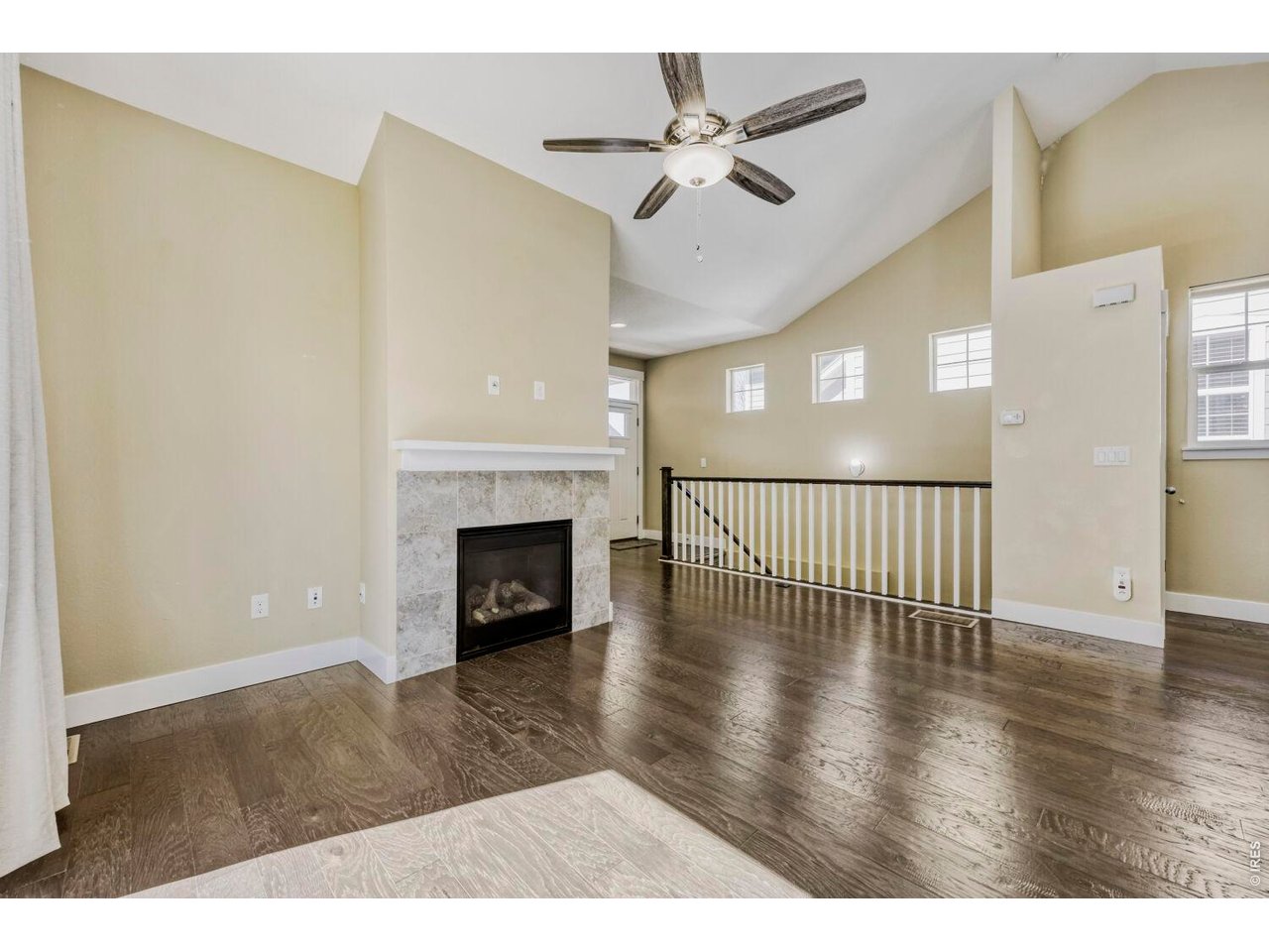 Expansive living room area with gas fireplace, ceiling fan and vaulted ceilings 