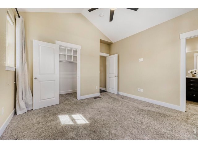 Property Photo 12 Master bedroom with walk-in closet, vaulted ceilings, ceiling fan, blinds, curtains and plush carpet