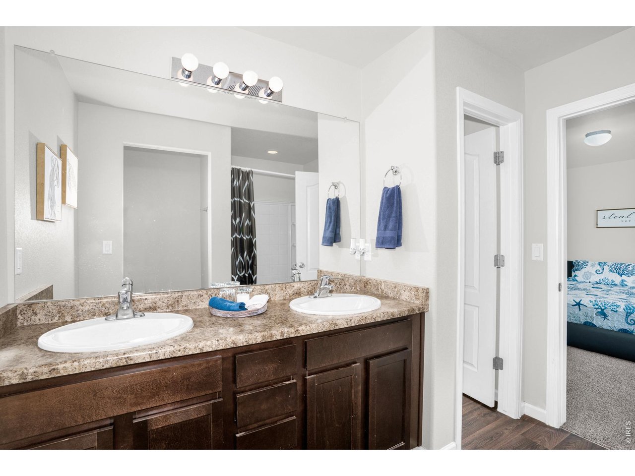 The primary ensuite bathroom features dual sinks, set within rich dark cabinetry that provides ample storage and complements the soft light-colored walls. The shower tub combo is ideal for quick routines and relaxing soaks! 