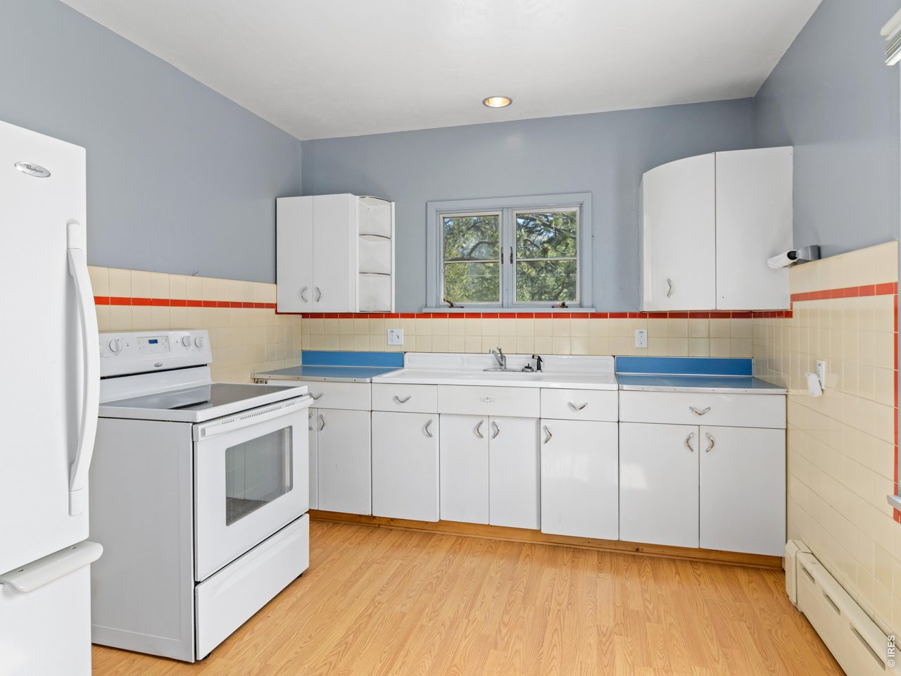 The kitchen is full of vintage character, showcasing original painted steel cabinets, a large farm sink, and timeless mountain-cabin appeal