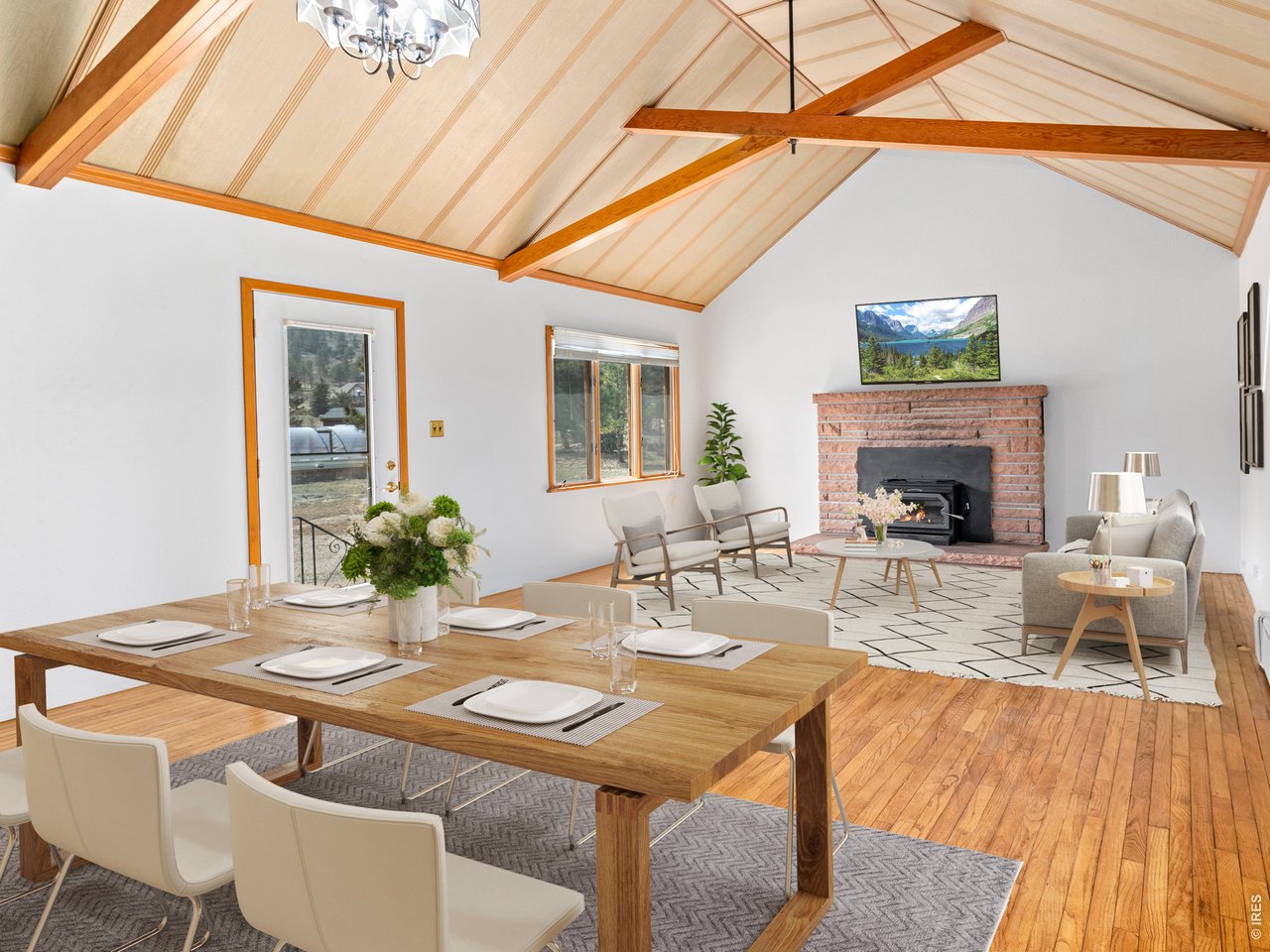 Spacious vaulted, beamed living room filled with natural light featuring hardwood floors and a stunning sandstone fireplace with an efficient wood-burning stove insert