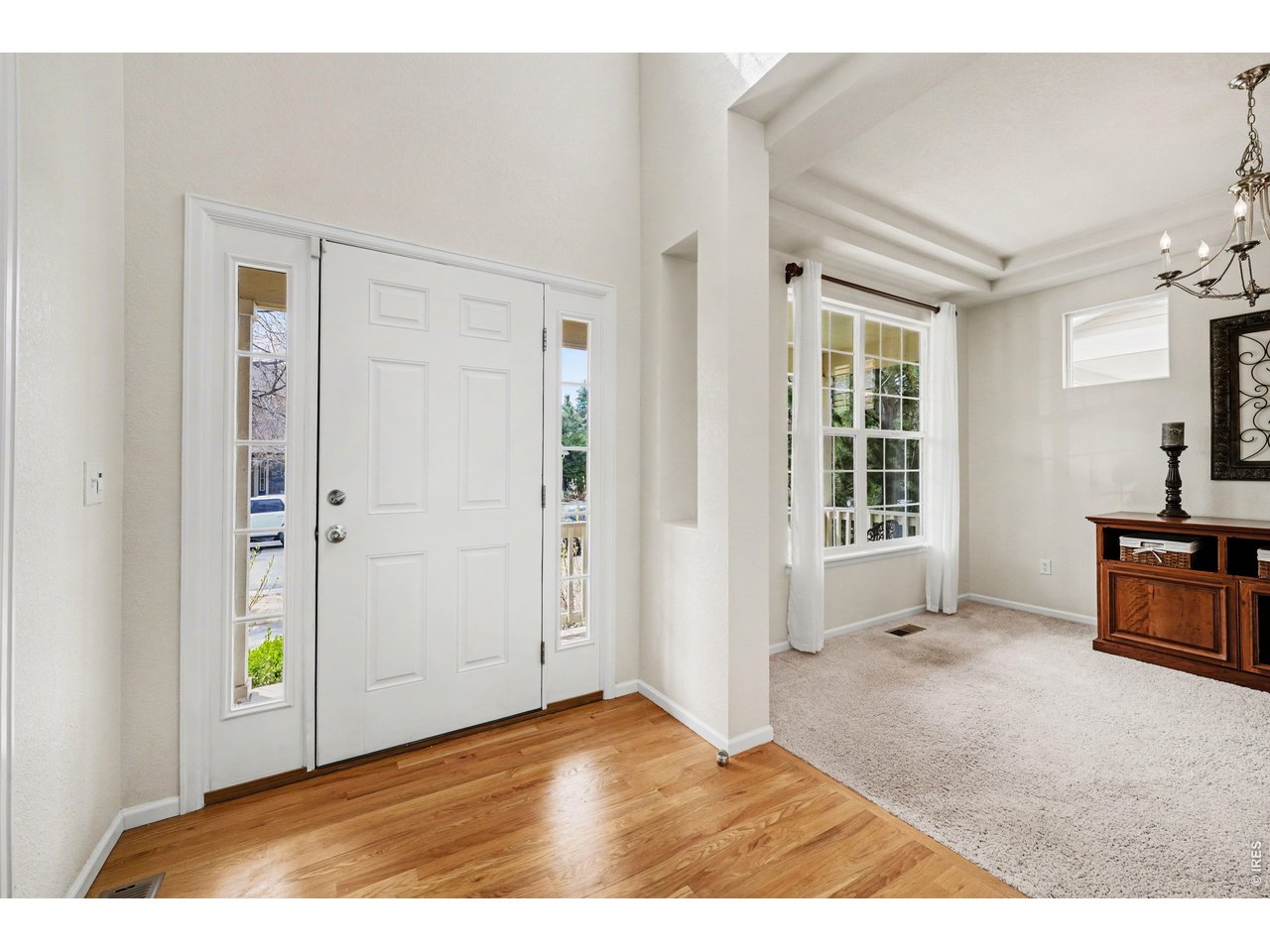 Bright, vaulted entryway leading into a formal living space or dining room