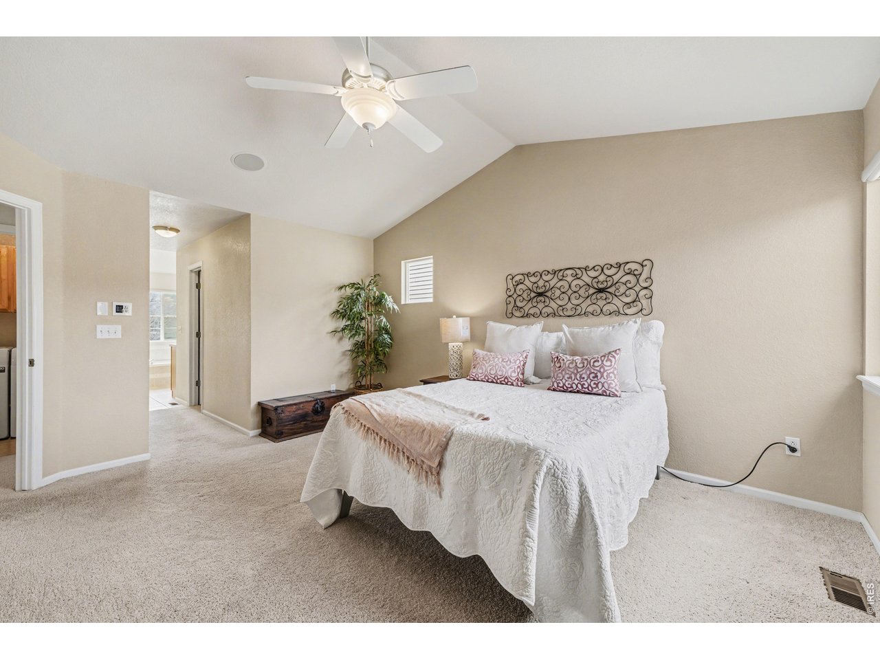 Serene primary bedroom with an open layout, featuring plush carpeting and a seamless transition to the ensuite bath