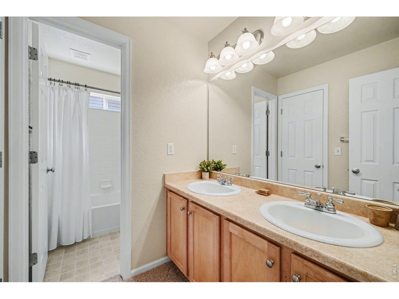 Shared bath offering a double vanity with plenty of storage and a large mirror