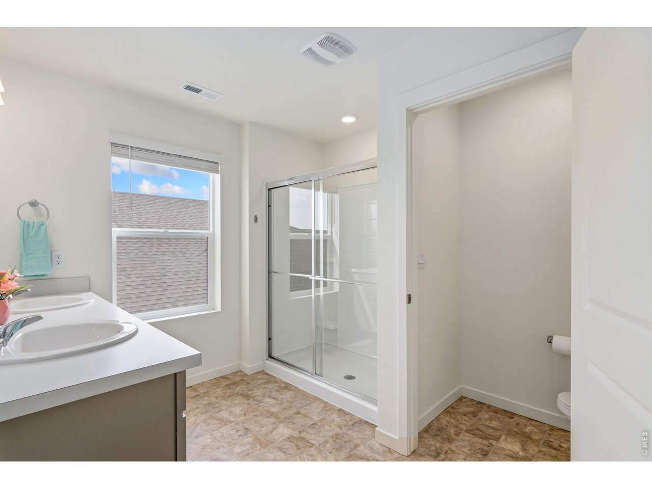 Primary bathroom featuring a walk-in shower & double sinks