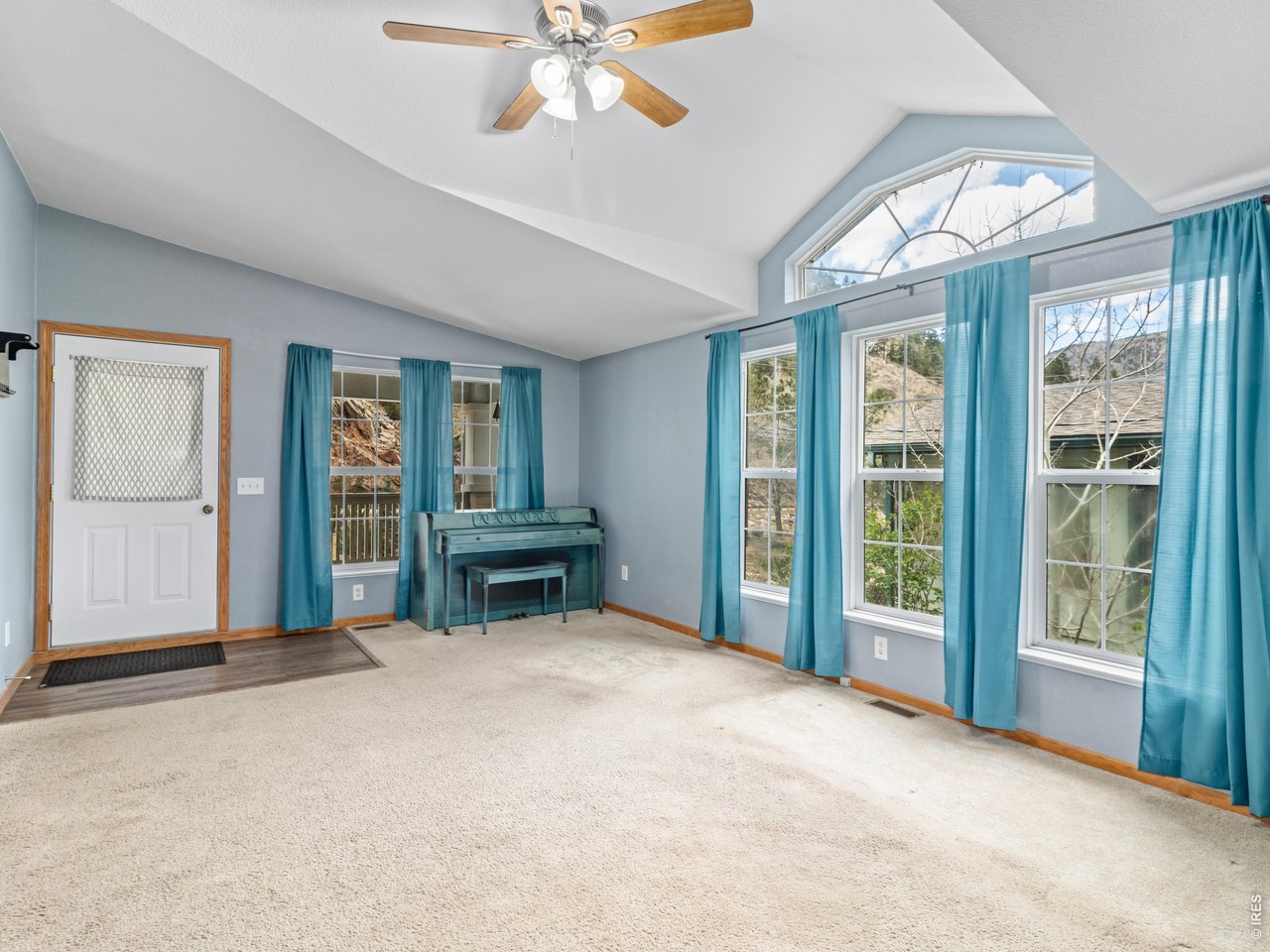 The living room features vaulted ceilings and an abundance of windows that fill the space with natural light, creating a bright and airy atmosphere