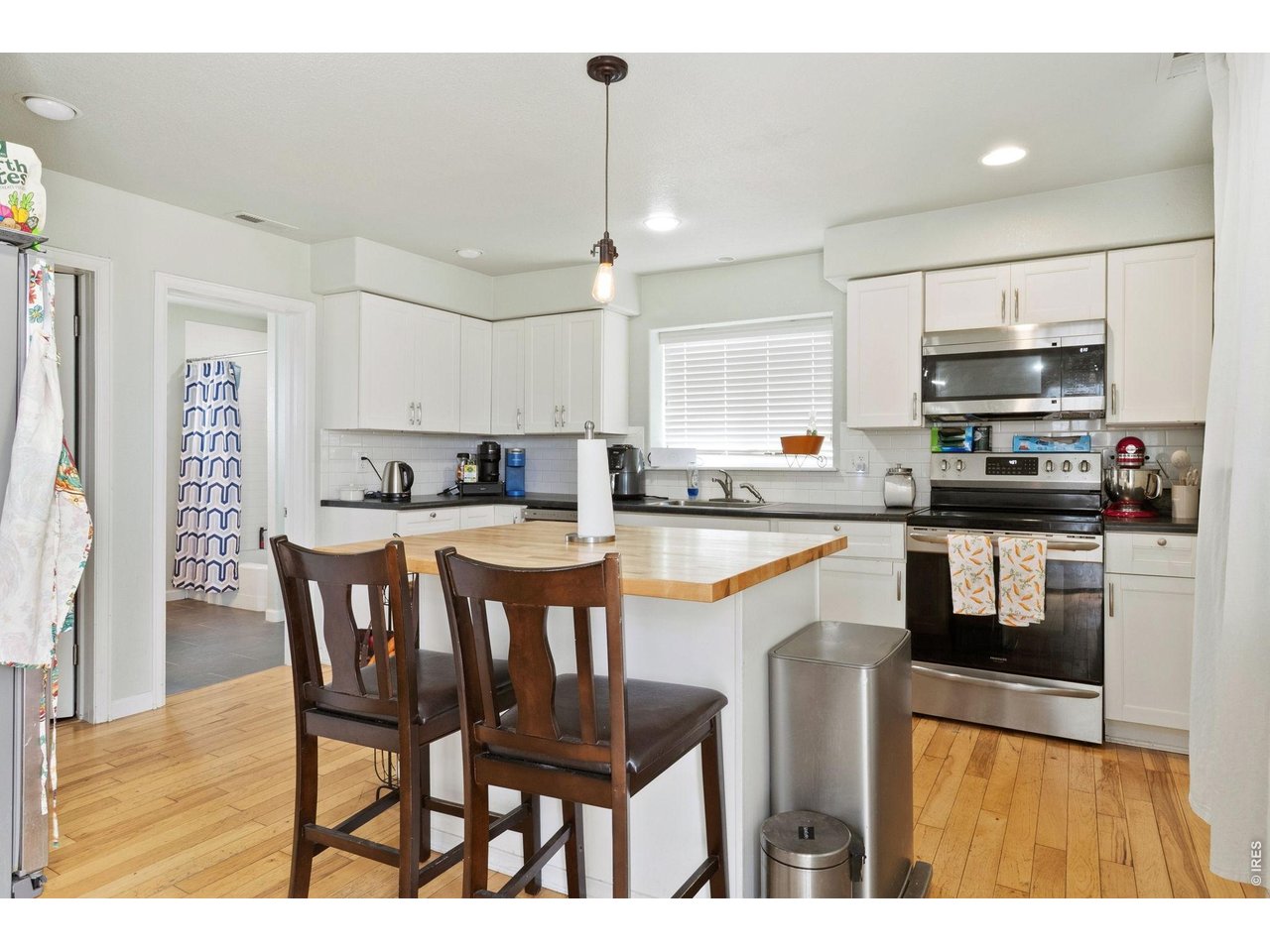 The kitchen showcases whitewashed cabinetry, upgraded appliances, subway tile backsplash, and a large butcher block island with seating.