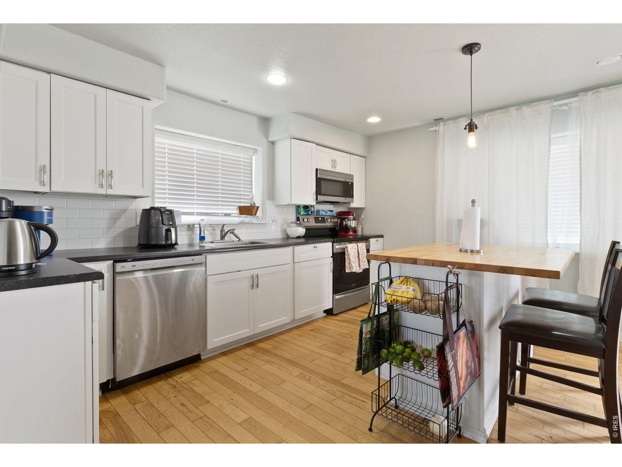 The kitchen showcases whitewashed cabinetry, upgraded appliances, subway tile backsplash, and a large butcher block island with seating