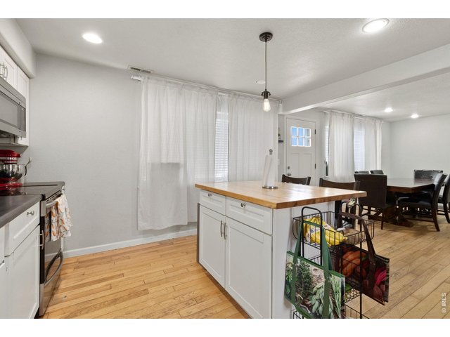 Property Photo 8 The kitchen showcases whitewashed cabinetry, upgraded appliances, subway tile backsplash, and a large butcher block island with seating.