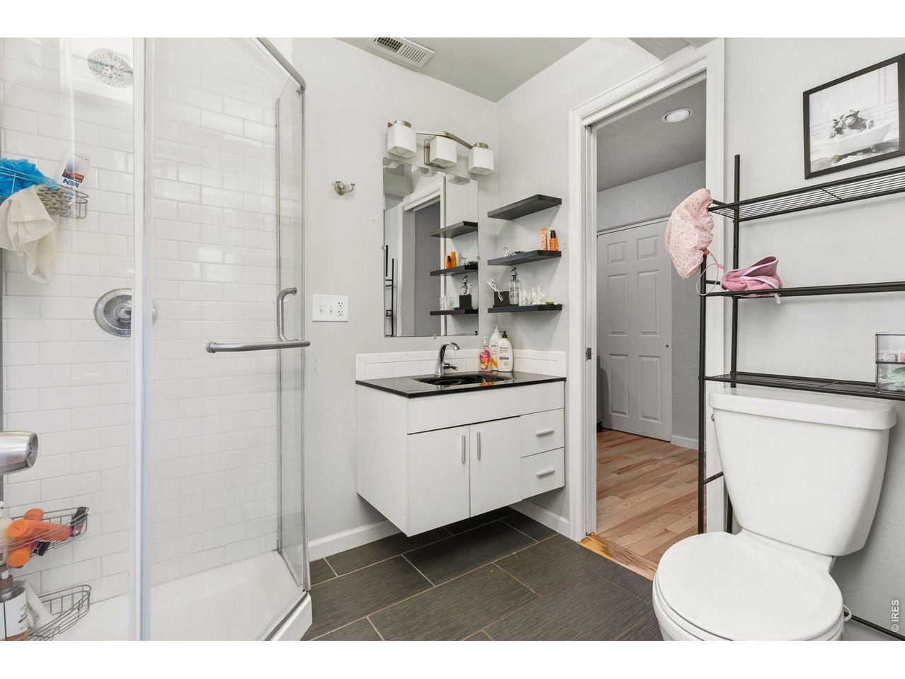 Primary bathroom with walk-in tile shower, updated tile flooring, updated vanity & lighting. 