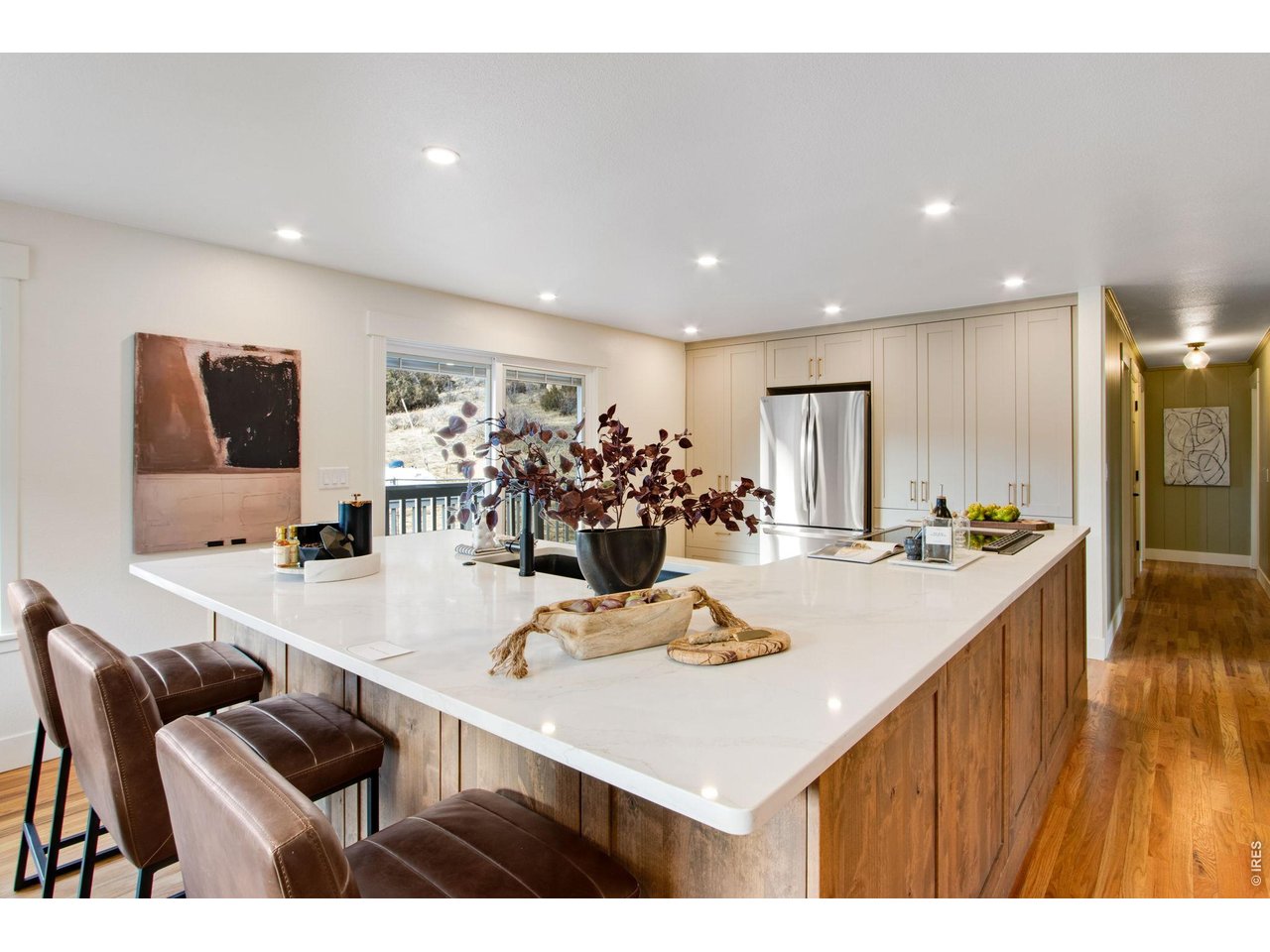The fully remodeled kitchen features quartz countertops, large center island, breakfast bar, pantry, abundant cabinets, & stainless steel appliances.