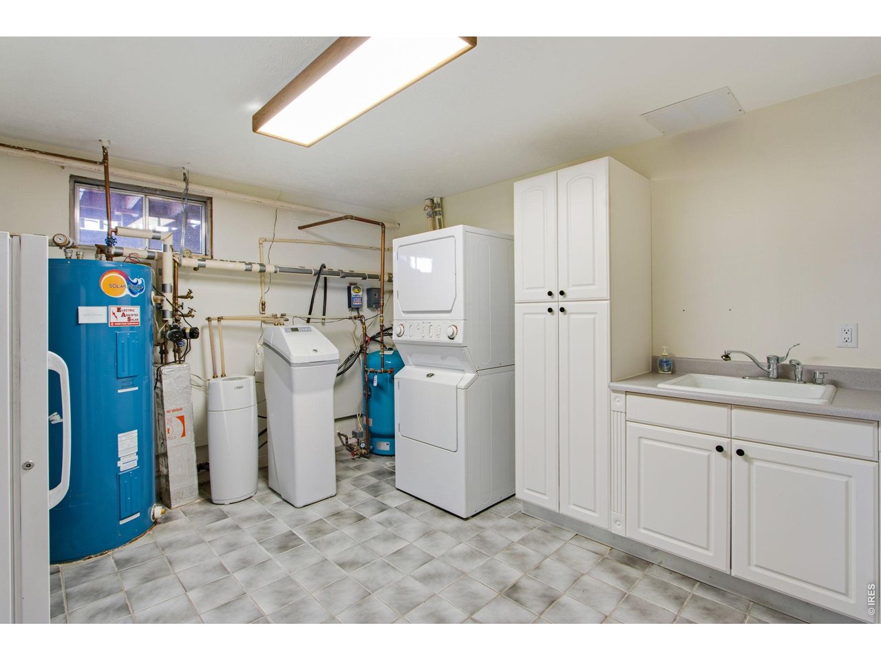 Laundry room features a linen closet, utility sink, under staircase storage and a stackable clothes washer and dryer which are included. Ample storage!