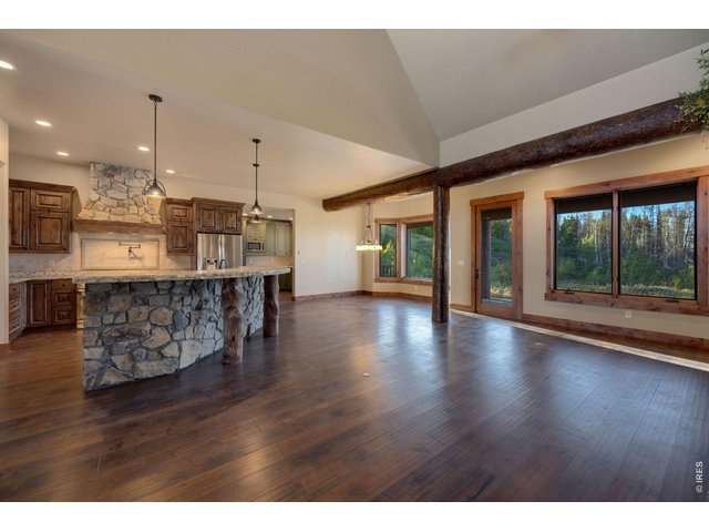 Property Photo 10 View of large kitchen, breakfast dining area, custom logs from the land, with large windows for plenty of natural light, and views of the fire pit