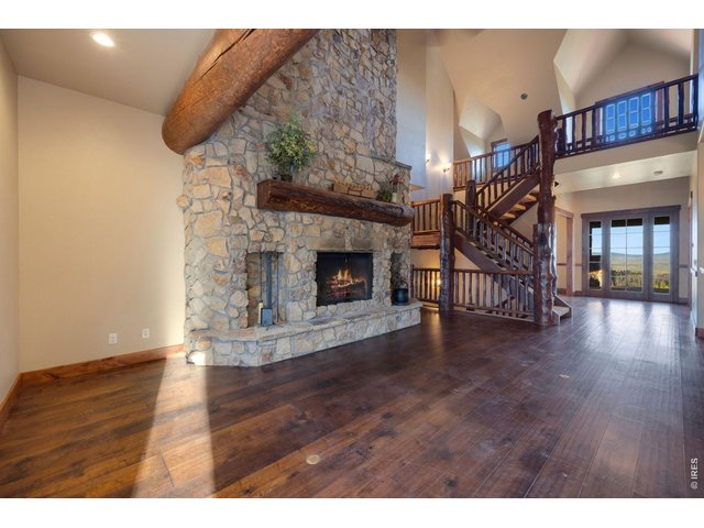 Property Photo 6 Large vaulted ceilings over the foyer and living room lead to the custom floor to ceiling fireplace complete with stones harvested from the land and in floor heating 