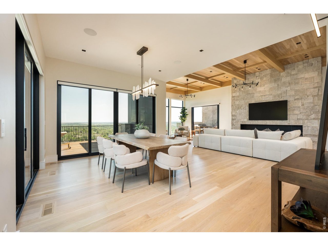 Elegant dining space encompassed by floor to ceiling windows and glass sliders offering access to the upper level outdoor living space. 