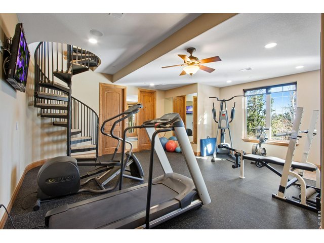 Property Photo 32 Gym with ceiling fan, TV, patio access, rubber flooring and mirrors included