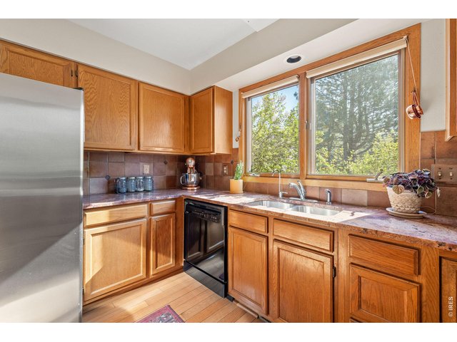 Property Photo 18 The large eat-in kitchen offers wood cabinetry, granite countertops, full-size appliances and oversized windows framing surrounding nature. 