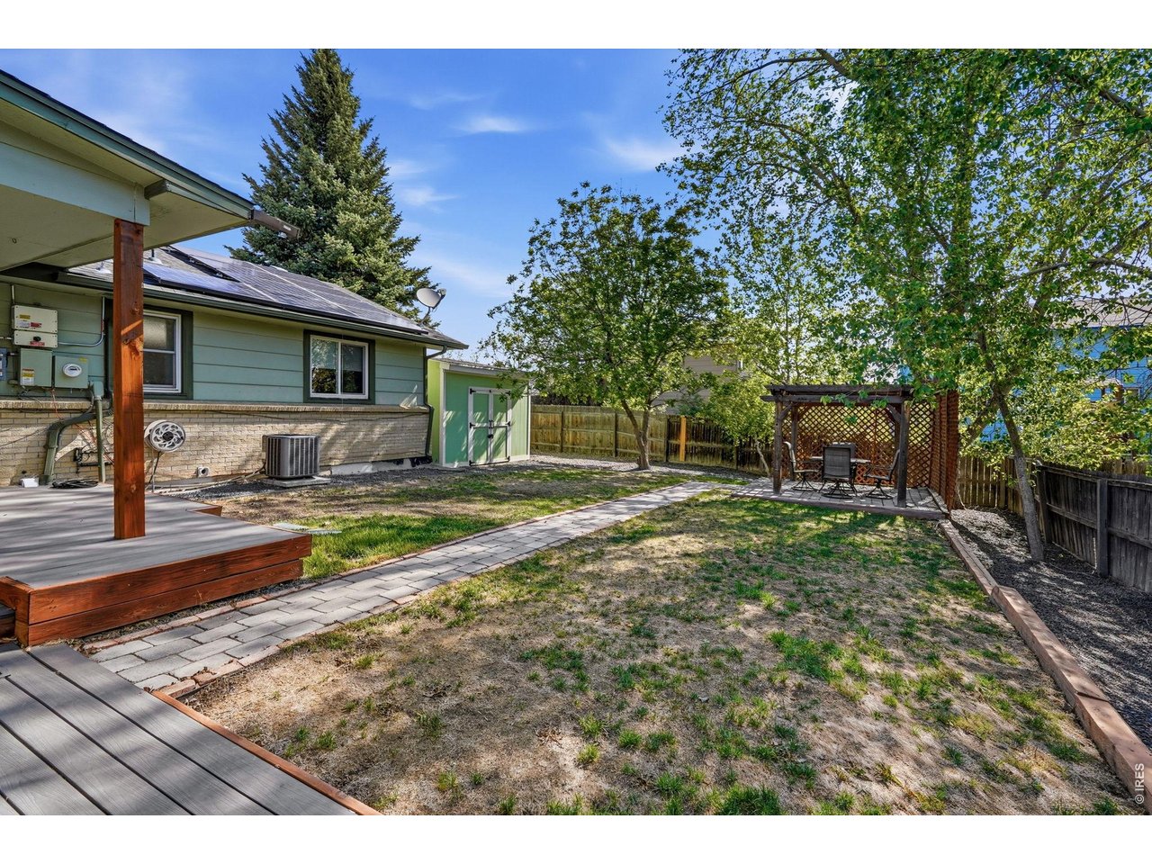 Private backyard oasis, complete with a Trex deck, pergola-covered patio, sprinkler system, and a concrete slab storage shed with electricity