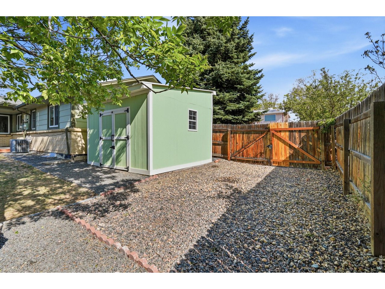 A side yard gravel driveway offers extra parking or storage for an RV or trailer, secured by a gate