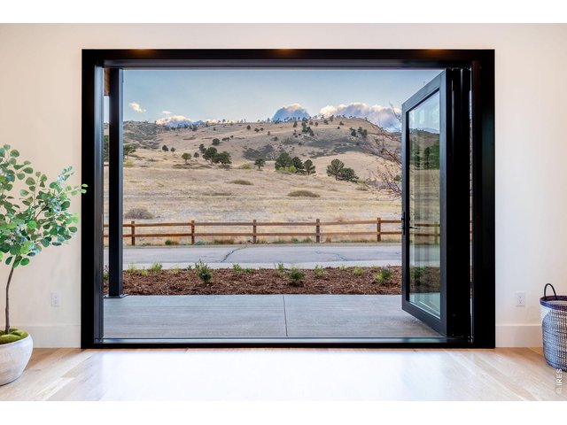 Property Photo 8 Retractable glass doors open the entire level to a wraparound covered porch and awe-inspiring foothills views. 