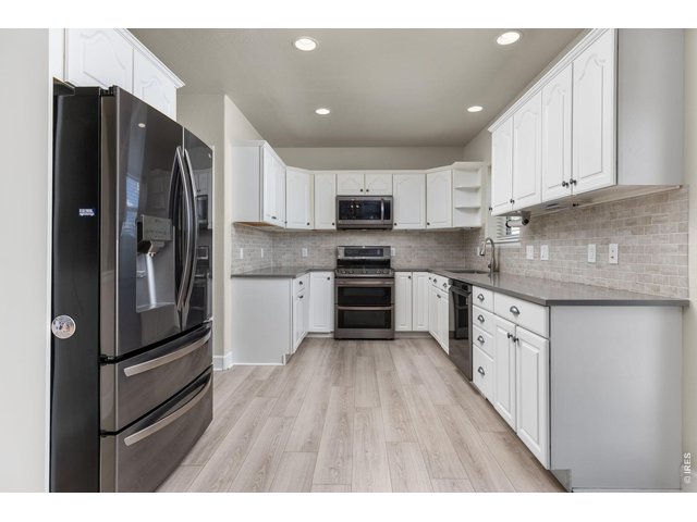 Property Photo 17 The kitchen has been updated with quartz countertops, subway tile backsplash, whitewash cabinetry, and newer appliances. 