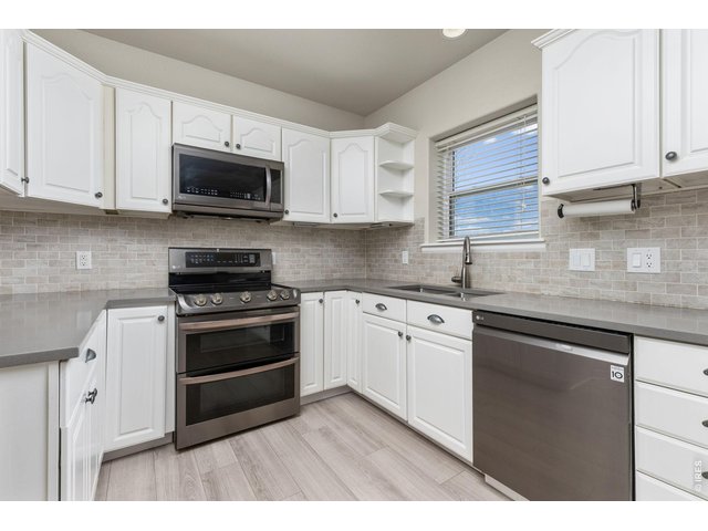 Property Photo 18 The kitchen has been updated with quartz countertops, subway tile backsplash, whitewash cabinetry, and newer appliances. 