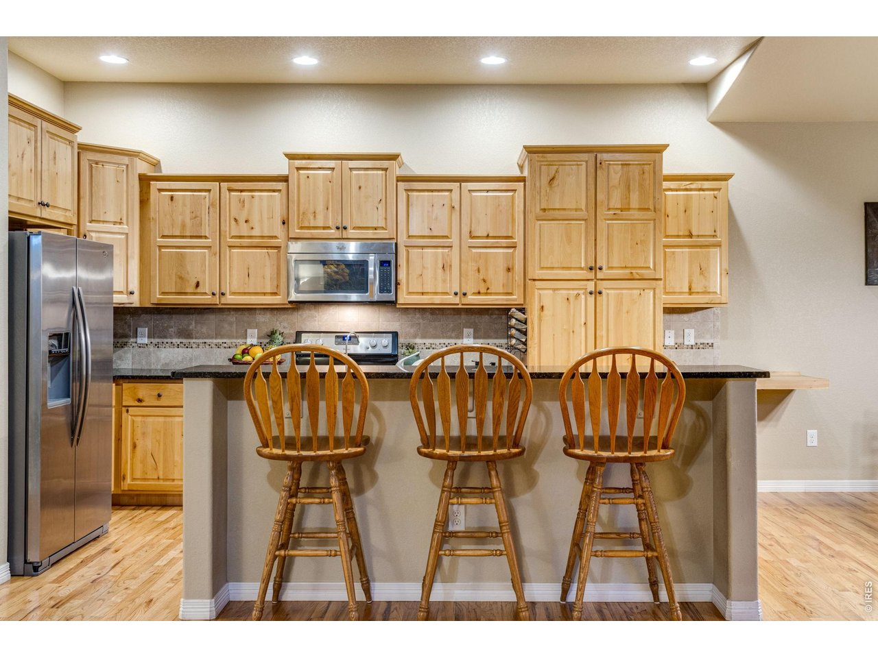 Center island, breakfast bar, pantry, granite slab countertops, cityscape knotty alder cabinetry with crown molding and hardware, full tile backsplash. 