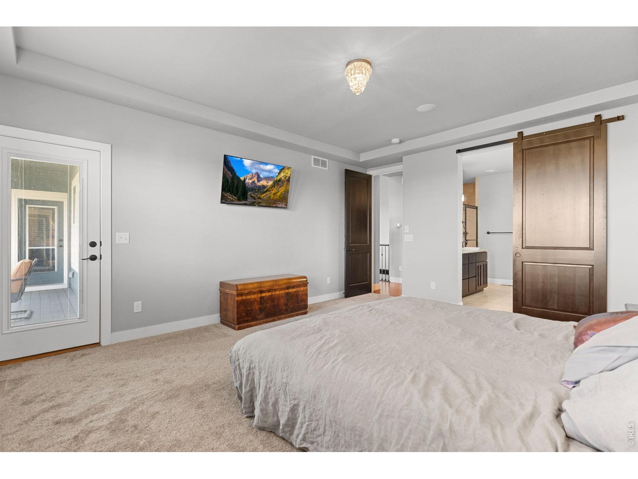 Primary bedroom w/ door to covered deck and sliding barn door