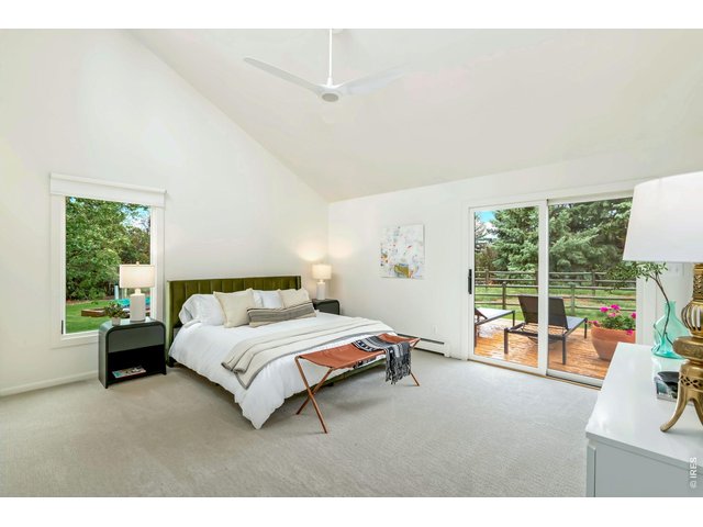 Property Photo 18 Main floor primary suite with soaring ceilings, sprawling views, and ensuite bath. Access to the deck and yard through the sliding-glass door. 