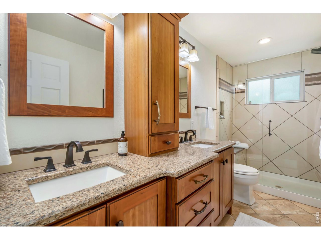 Master bathroom with double sinks, and glass shower with a bench. 