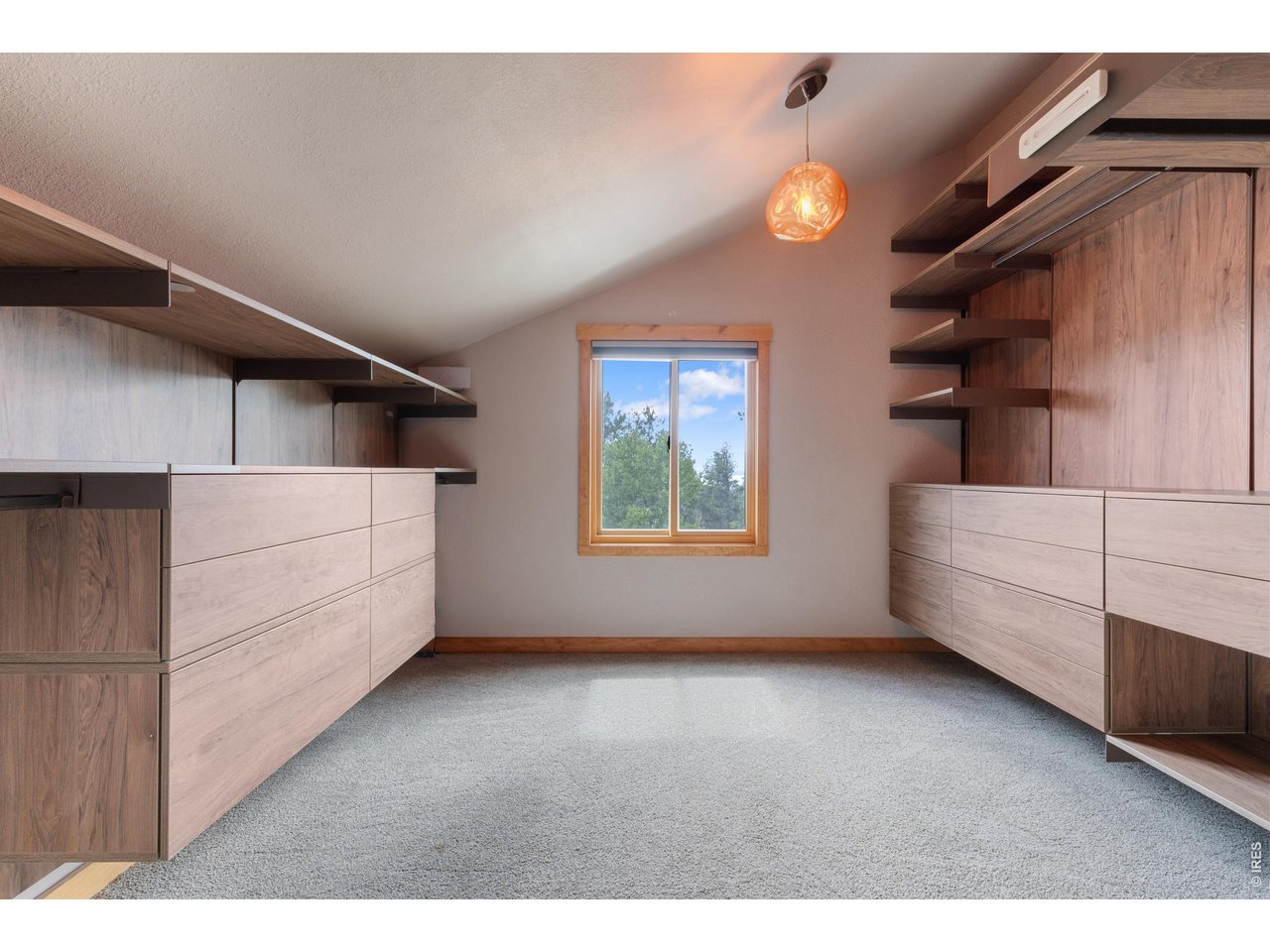Designer closet with under shelving lighting and unique hanging light.