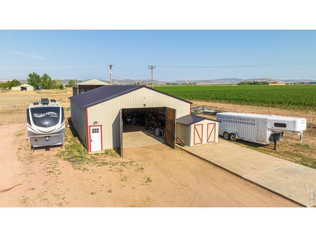 Property Photo 11 A 1,545 sq ft detached drive-through RV/boat garage & shop features 220V, added electrical, air compressor, & included shelving, cabinets, & workbench.