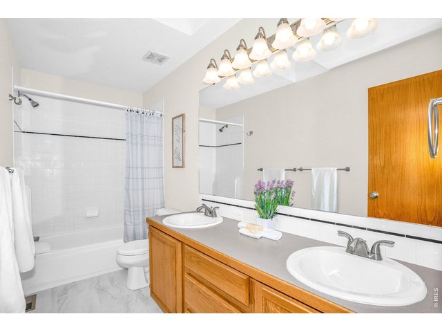 Property Photo 27 The shared full bath upstairs sits perfectly between all bedrooms. With dual sinks, newer lighting, and a skylight, this bathroom is bathed in light. 