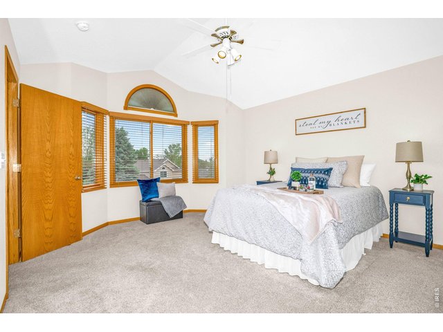 Property Photo 16 The large primary bedroom has vaulted ceilings, neutral paint, and large windows for plenty of natural light. 