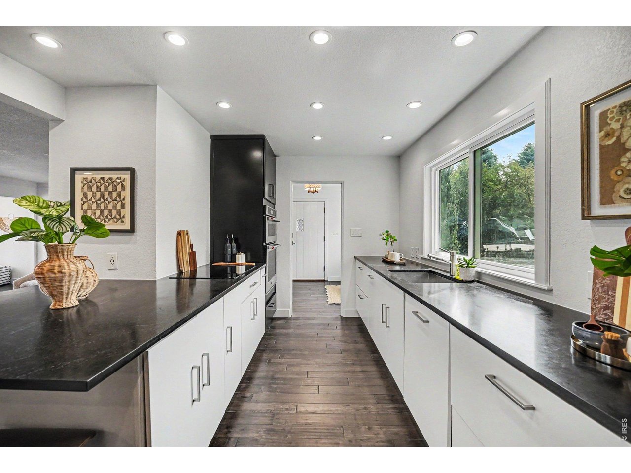 Modernized kitchen highlighting ample counter space and smart storage. Bright recessed lighting and a large window make this functional, open workspace feel incredibly inviting.