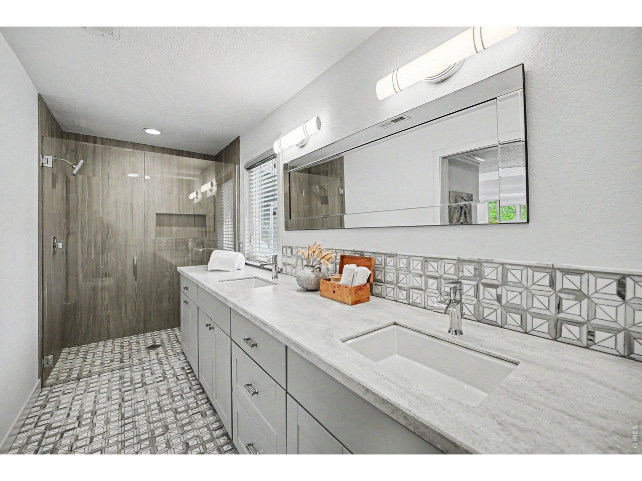 Spa-like primary bathroom retreat! Fully updated with a massive double-sink vanity, light stone countertops, geometric accent tiling, and modern lighting. Highlights include a stunning, custom floor-to-ceiling tiled, zero entry glass shower.