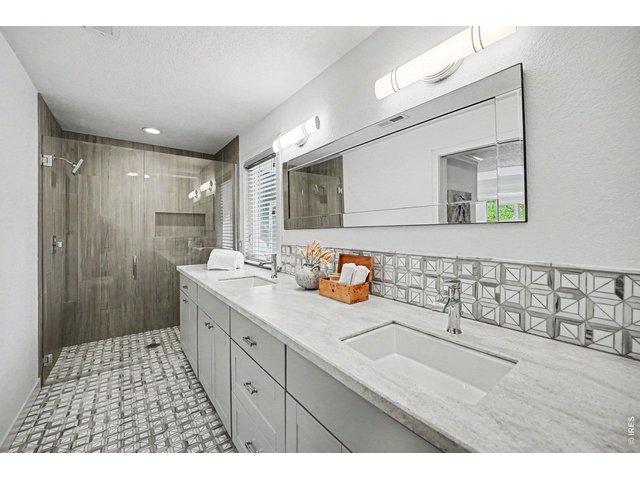 Property Photo 15 Spa-like primary bathroom retreat! Fully updated with a massive double-sink vanity, light stone countertops, geometric accent tiling, and modern lighting. Highlights include a stunning, custom floor-to-ceiling tiled, zero entry glass shower.