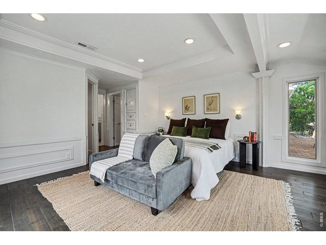 Property Photo 13 Spacious primary bedroom showcasing beautiful custom millwork, wainscoting, and recessed lighting. The open layout easily accommodates a seating area, adding a high-end resort feel to this premium space.