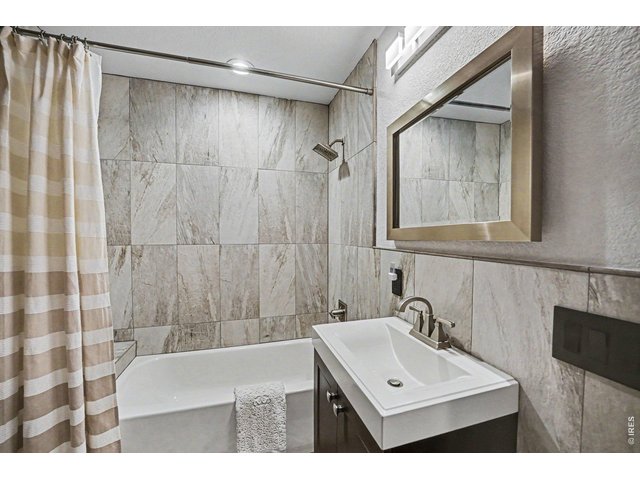 Property Photo 20 Beautifully remodeled secondary bathroom. Features a modern espresso vanity with a crisp white basin sink, updated brushed nickel fixtures, and a stunning custom floor-to-ceiling tile.