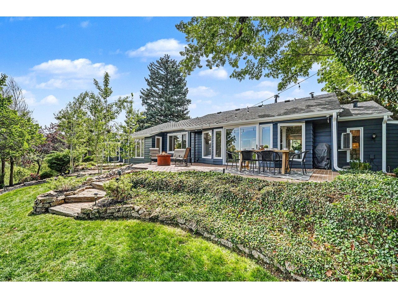 Stunning terraced lawn featuring custom stone staircases, detailed rock garden beds, and massive mature trees creating a peaceful, shaded oasis.