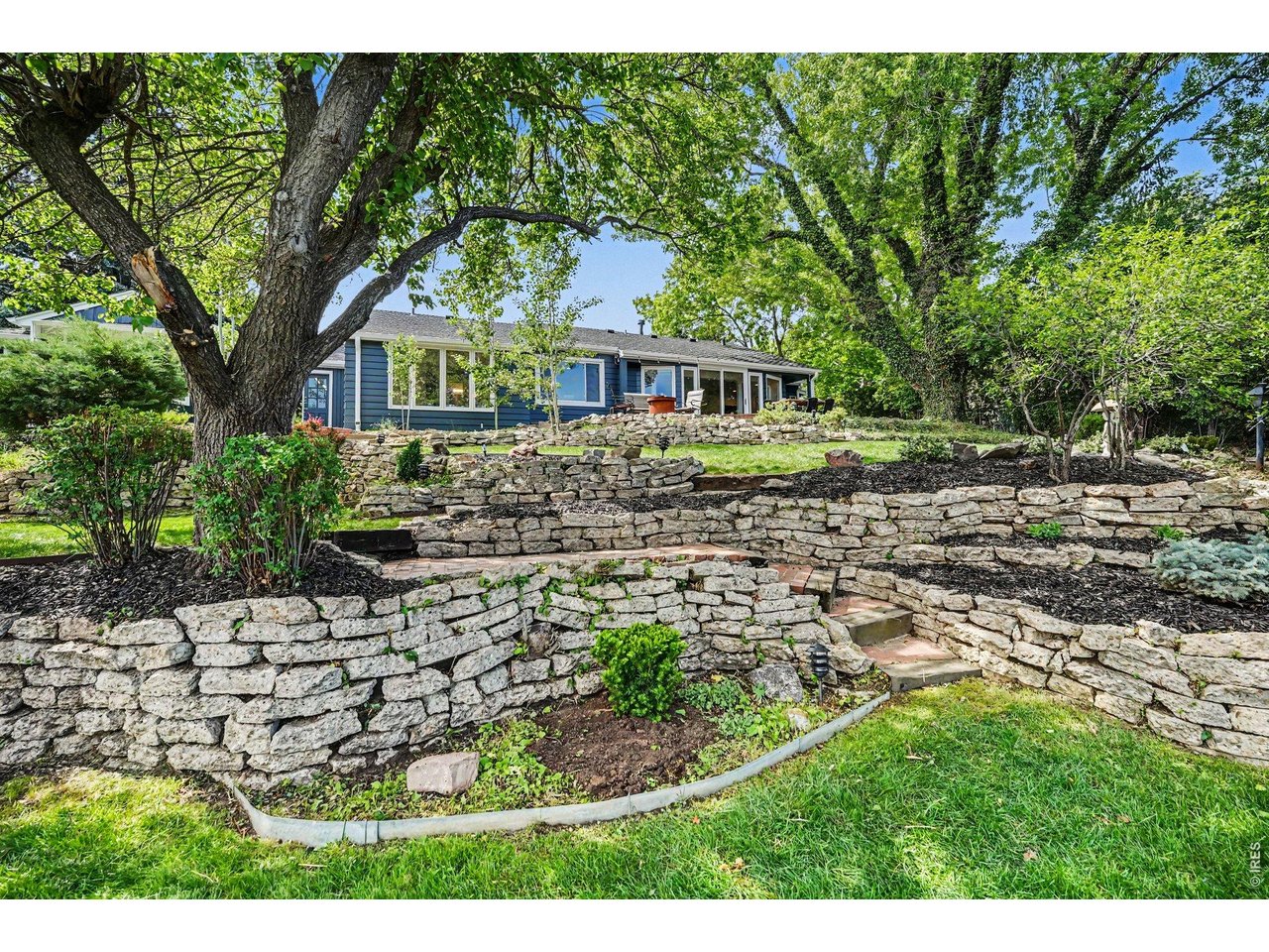 Impressive, multi-level dry-stack stone retaining walls, integrated walking paths, lush green spaces, and a magnificent canopy of mature trees.